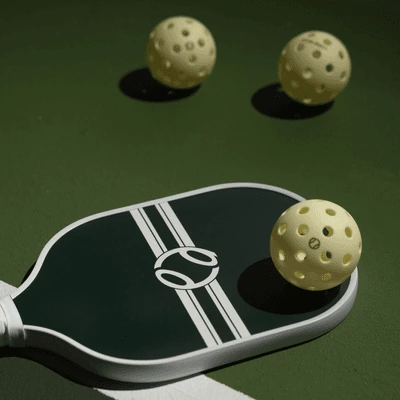 Pickleball paddle and balls on a PickleDepot court